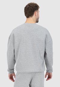 Felpa grigia con un fit rilassato, scollatura rotonda e spalle cadenti. Tessuto morbido con dettagli di cucitura minimi. Adatta per un look casual.