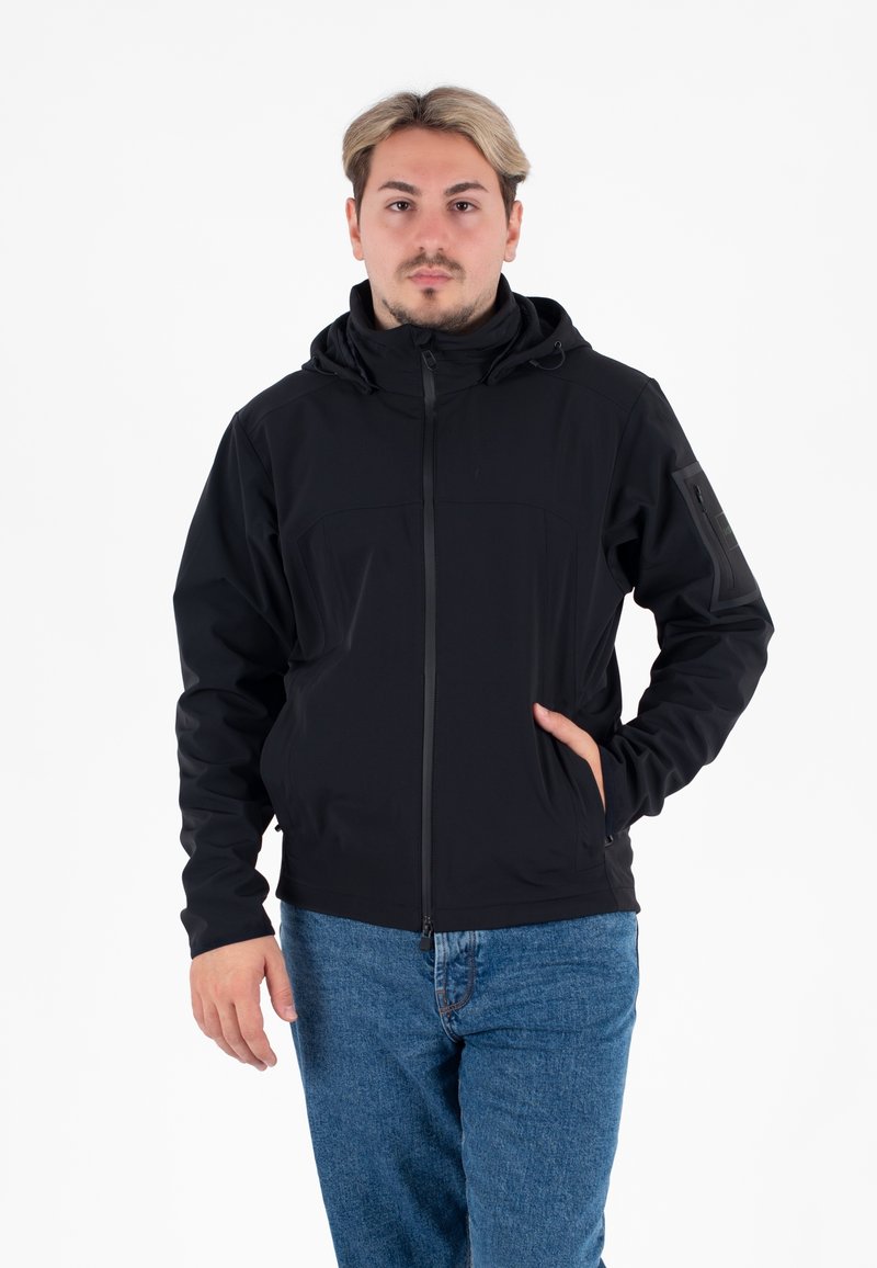 Giacca softshell nera con cappuccio, zip frontale e due tasche laterali. Presenta un tessuto testurizzato e una silhouette slanciata e aderente.