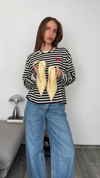 Décolleté slingback in materiale giallo chiaro, con dettagli arricciati e cinturini sottili, indossate da una persona in camicia a righe.