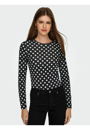 Haut noir à manches longues avec des pois blancs, encolure ronde et coupe ajustée, associé à un jean noir taille haute.