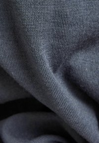 Mörkgrå stickad tyg med en slät yta, med fin sömnad och lätt elasticitet, som hänger mjukt i veck.