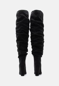 Sorte over-knee støvler lavet af struktureret ruskind med rynkedesign og sølvprikkede detaljer, der har chunky hæle og lynlås.