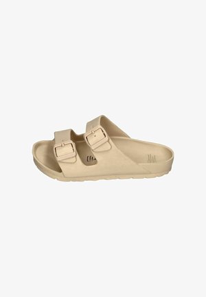 Zwei beige Sandalen mit Schnallen, die auf klarem blauem Schwimmbadwasser mit Lichtreflexionen und Wassertropfen auf den Sandalen schweben.