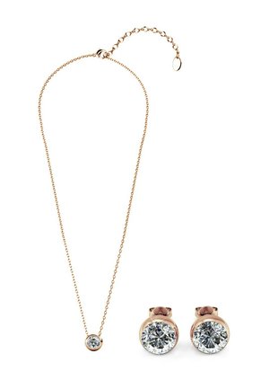 Set di gioielli in tonalità oro composto da una delicata collana con un pendente rotondo e orecchini a bottone coordinati, entrambi impreziositi da gemme trasparenti e rotonde.