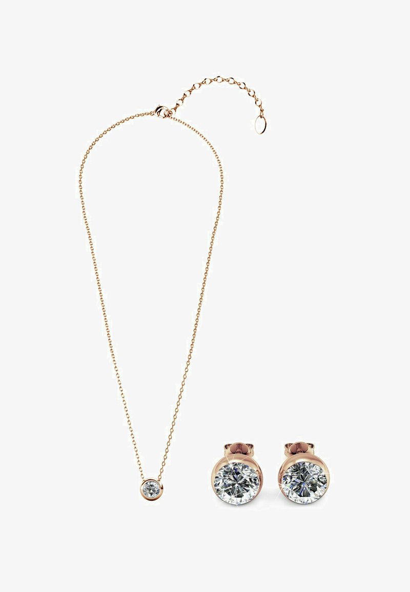 Set di gioielli in tonalità oro composto da una delicata collana con un pendente rotondo e orecchini a bottone coordinati, entrambi impreziositi da gemme trasparenti e rotonde.