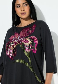 Černý top s květinovým vzorem z flitrů v odstínech růžové, zlaté a zelené. Rukávy do tří čtvrtin a kulatý výstřih.