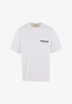 T-shirt bianco in cotone con maniche corte, scollo rotondo e logo stampato sulla parte sinistra del petto. Design semplice e classico.