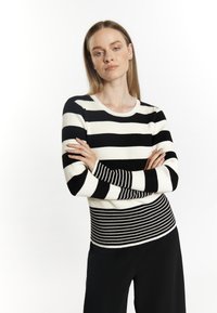 Czarno-biała striped sweter z długim rękawem o prążkowanej fakturze. Paski różnią się szerokością, z dopasowanym pasem w talii. Okrągły dekolt.