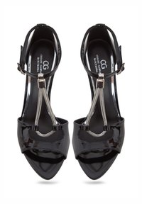 Sandales à talons hauts en cuir verni noir avec un bout pointu, une sangle de cheville, des accessoires métalliques et des accents de chaîne décoratifs.