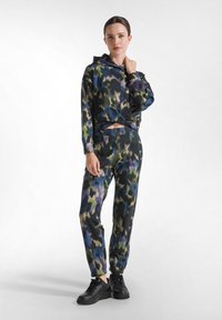 Set di felpa con cappuccio e pantaloni in un motivo astratto multicolore. Realizzato in tessuto morbido, presenta un fronte annodato e polsini elasticizzati. Sneakers nere.
