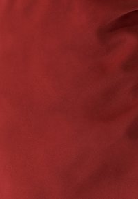 Punainen mokkanahka, pehmeä rakenne matalla pinnalla, jossa on hienovaraisia sävyeroja ja sileä, tasainen pinta.