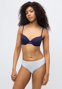 Μπλε σκούρο σουτιέν με απαλό ύφασμα και χωρίς ραφές, με μικρό φιόγκο στο κέντρο· ανοιχτό μπλε σλιπ ψηλόμεσο με λεπτομέρειες από δαντέλα.