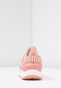 Zapatilla deportiva rosa con tejido texturizado, collar acolchado y audaz logotipo "PUMA" en el talón. Media suela blanca y suela de goma.