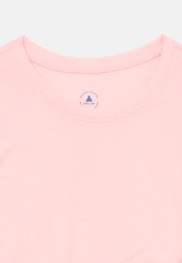 Roze dječja majica sa okruglim izrezom i malom plavom otiskom oznake koja prikazuje medvjedića i tekst "baby gap" unutar ovratnika.