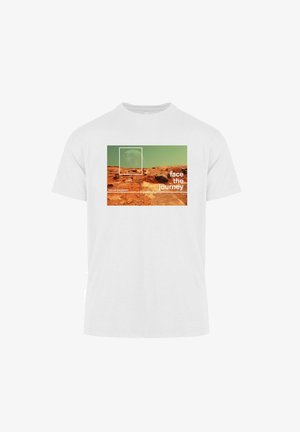 T-shirt en coton blanc avec un graphisme d'un paysage rocheux, un ciel vert et le texte "affronter le voyage" en police grasse et moderne.