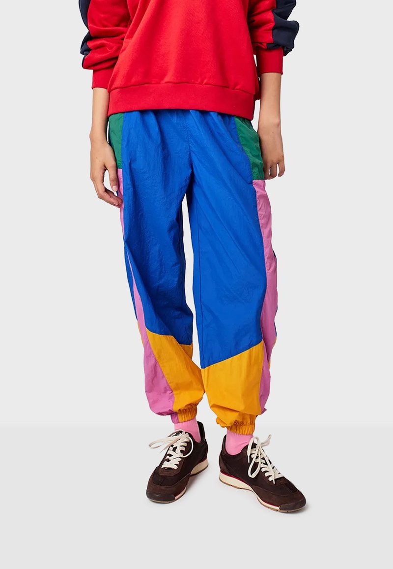 Multikleur trackpants met blauwe, roze, groene en gele panelen. Gemaakt van lichtgewicht materiaal met enkelsluitingen en een relaxte pasvorm.