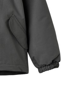 Szara kurtka wykonana z fakturowanej tkaniny, z elastycznymi mankietami i boczną kieszenią z klapką. Projekt jest smukły, o nowoczesnym kroju.