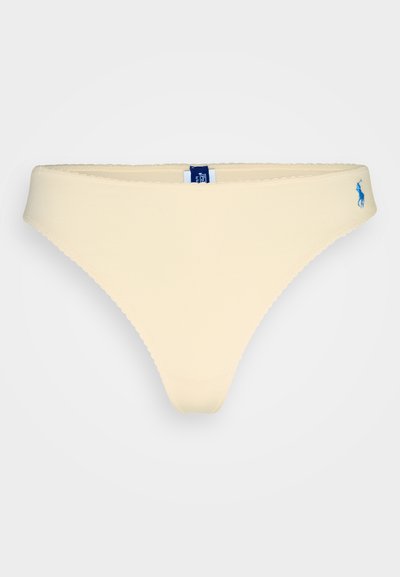 Lys gul bikini-thong med en glatt tekstur, bølgete kanter og en liten blå logo aksent bak.