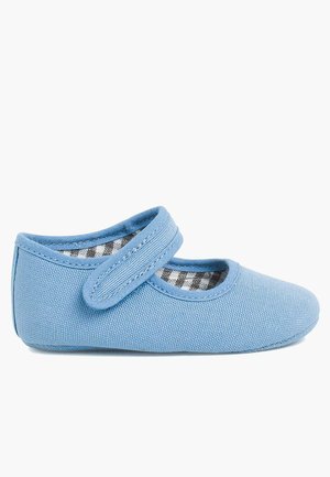 Zapatilla de lona azul con punta redondeada, tira ajustable y forro a cuadros. Suela plana, textura suave y diseño sencillo.