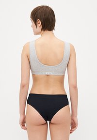Harmaa puuvillabralette, jossa on leveät hihnat ja matala selkä, yhdistettynä mustiin puuvillapikkareihin, joissa on sileä pinta ja minimalistinen muotoilu.