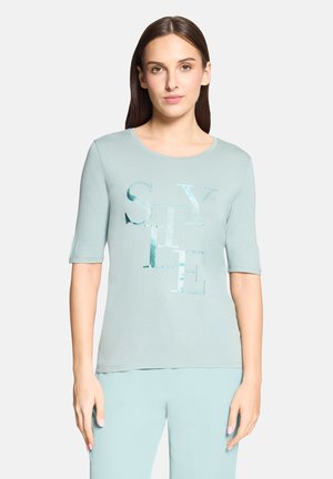 Lyseblå T-shirt med korte ærmer og rund halsudskæring, der har et grafisk "STYLE" design i forskellige blå nuancer og skinnende detaljer.