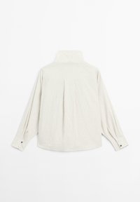 Lettet tekstureret, stribet skjorte med høj krave, lange ærmer og knappede manchetter i en neutral beige farve. Har en rygfold detaljer.