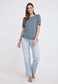 Blommönstrad kortärmad topp i mörkblått, matchad med ljusblå raka jeans. Mjuk tyg och avslappnad passform med sidofickor.