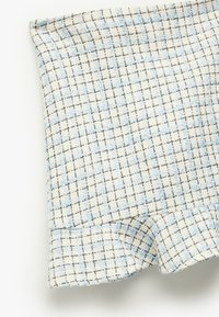 Tissu texturé en crème avec un motif en grille de fils noir et bleu clair ; présente un bord effiloché et une texture douce et tissée.