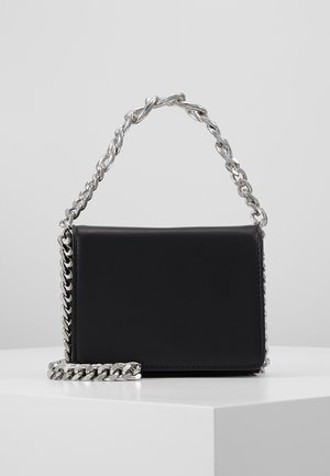 Sac à main rectangulaire noir avec anse en chaîne argentée et garniture, présenté sur un socle blanc sur fond gris clair uni.