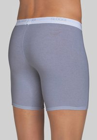 Pantaloni corti grigi in cotone con un elastico bianco contrassegnato "SLOGGI". Il tessuto sembra liscio, offrendo una vestibilità aderente e una lunghezza fino a metà coscia.