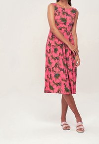 Blumenmuster Kleid in leuchtendem Pink mit einem knielangen Rock. Hergestellt aus leichtem Stoff, hat es ein ärmelloses Design und eine taillierte Passform.