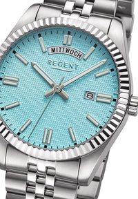 Montre en acier inoxydable avec un cadran turquoise texturé, affichage de la date, index argentés et une lunette polie à cannelures.