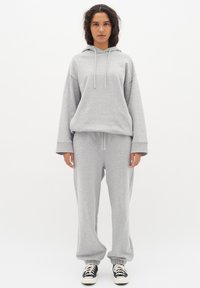 Grå sweatshirt med huva och dragsko, matchad med svarta joggers. Mjuk kvalitet, avslappnad passform, ribbad mudd och midja.