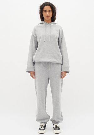 Grijze sweatshirt met capuchon en koord, gecombineerd met bijpassende sweatpants. Zachte stof, ontspannen pasvorm, ribgebreide manchetten en tailleband.
