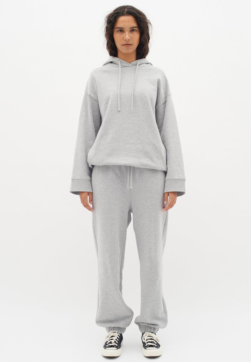 Grå sweatshirt med huva och dragsko, matchad med svarta joggers. Mjuk kvalitet, avslappnad passform, ribbad mudd och midja.