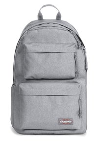 Mochila de tela gris con dos bolsillos frontales con cremallera, respaldo acolchado y detalles cosidos. Presenta el logo de Eastpak en la parte frontal inferior.