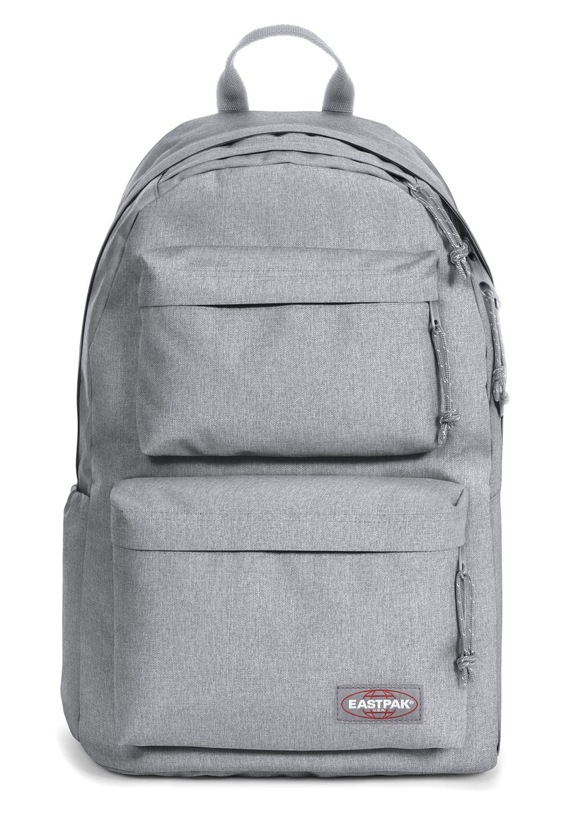 Mochila de tela gris con dos bolsillos frontales con cremallera, respaldo acolchado y detalles cosidos. Presenta el logo de Eastpak en la parte frontal inferior.