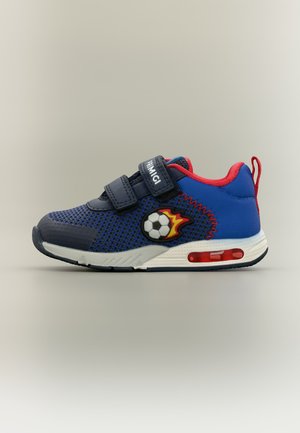 Dječja plava i crvena tenisica s čičak trakama i dizajnom zapaljene nogometne lopte sa strane, na neutralnoj pozadini.