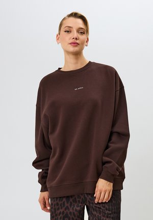 Sudadera de algodón marrón con un corte relajado, escote redondo y texto impreso "OH ABRIL" en el pecho, combinada con pantalones de leopardo.