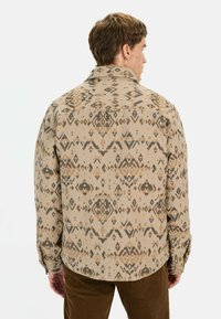 Beige shirt met een geometrisch ontwerp in bruin en zwart, met een losse pasvorm en knoopmanchetten.