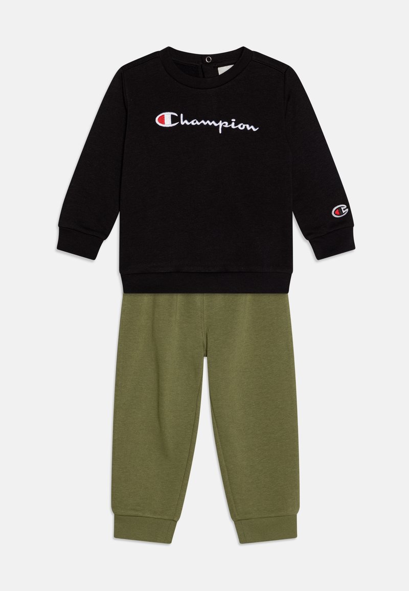 Felpa nera con logo bianco "Champion", abbinata a pantaloni della tuta in cotone verdi. Entrambi presentano polsini a coste e una vestibilità comoda.