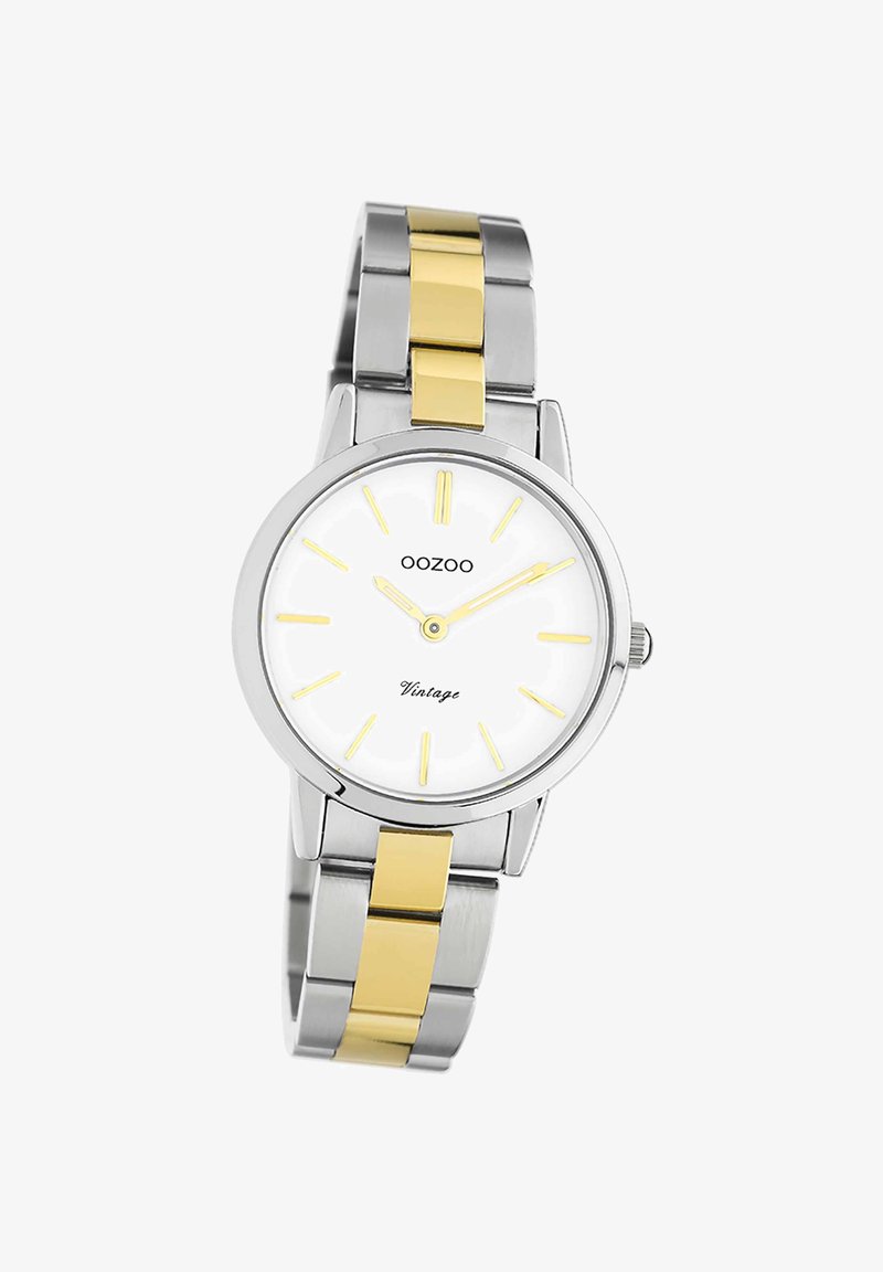 Montre argentée et dorée avec un cadran blanc, des marqueurs d'heure jaunes et des aiguilles délicates. Bracelet en acier inoxydable avec des maillons dorés alternés.