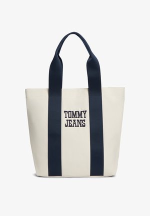 Bež platnena torba z dvema širokima mornarsko modrima trakovoma in vezenim napisom "TOMMY JEANS" v mornarsko modri barvi na sredini sprednje strani.