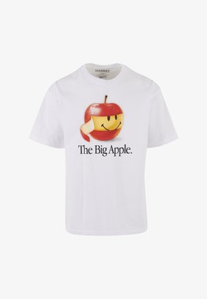 Valge puuvillane T-särk, millel on suur graafika naeratava õuna kujutisega, millel on punane ja kollane disain, koos tekstiga "Suurel Õunal."