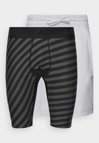 Pantalones cortos deportivos a rayas negras y grises con una cintura elástica, superpuestos sobre pantalones cortos blancos con cordón. Ambos cuentan con un tejido transpirable.