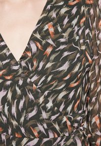 Vestido envolvente en una tela ligera y texturizada que presenta un patrón abstracto multicolor sobre un fondo oscuro. Escote en V profundo y detalle de lazo.