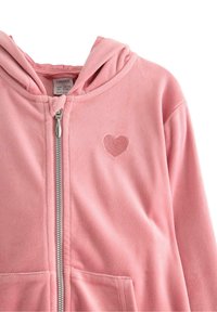 Polarowa bluza z kapturem w jasnoróżowym kolorze z zamkiem błyskawicznym z przodu i małą haftowaną łatą w kształcie serca. Posiada kaptur oraz dwie przednie kieszenie.