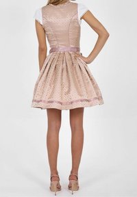Hellrosa Kleid mit körperbetontem Oberteil, plissiertem Rock, geometrischen Mustern und einem Satin-Gürtel. Getragen mit hellfarbigen Riemchenschuhen.