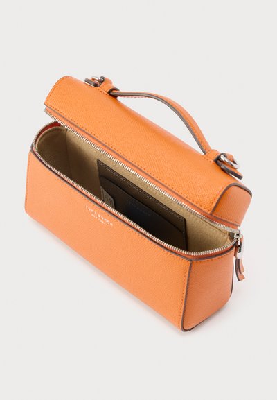 Πορτοκαλί δερμάτινο πορτοφόλι καρπού με ανοιχτό φερμουάρ, που δείχνει μπεζ εσωτερικό και μαύρη θήκη καρτών μέσα, με επάνω λαβή και ασημένια μεταλλικά μέρη.