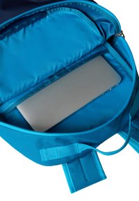 Blå ryggsekk med polstret rom for en slank sølv laptop, glatt stoff og glidelåslukking. Justerbare stropper synlige.